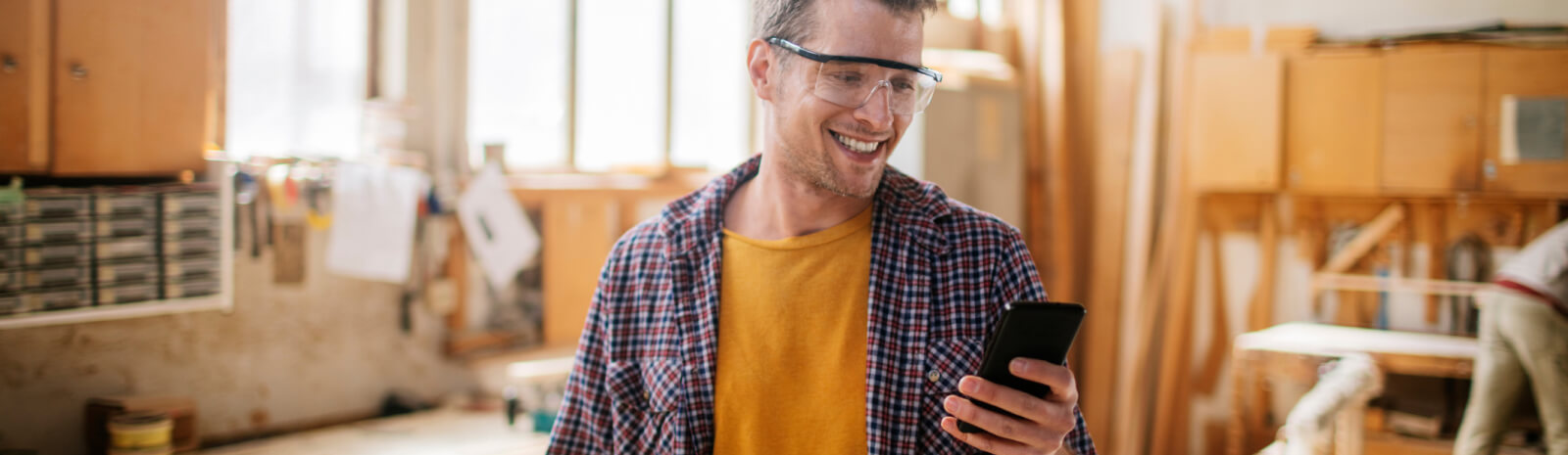 man wearing safety glasses looking at a smartphone